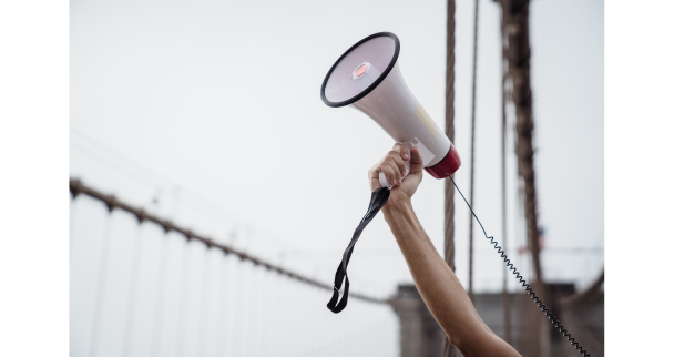 An image of a megaphone being held in the air, symbolizing advocacy, amplifying voices, and taking action for a cause.